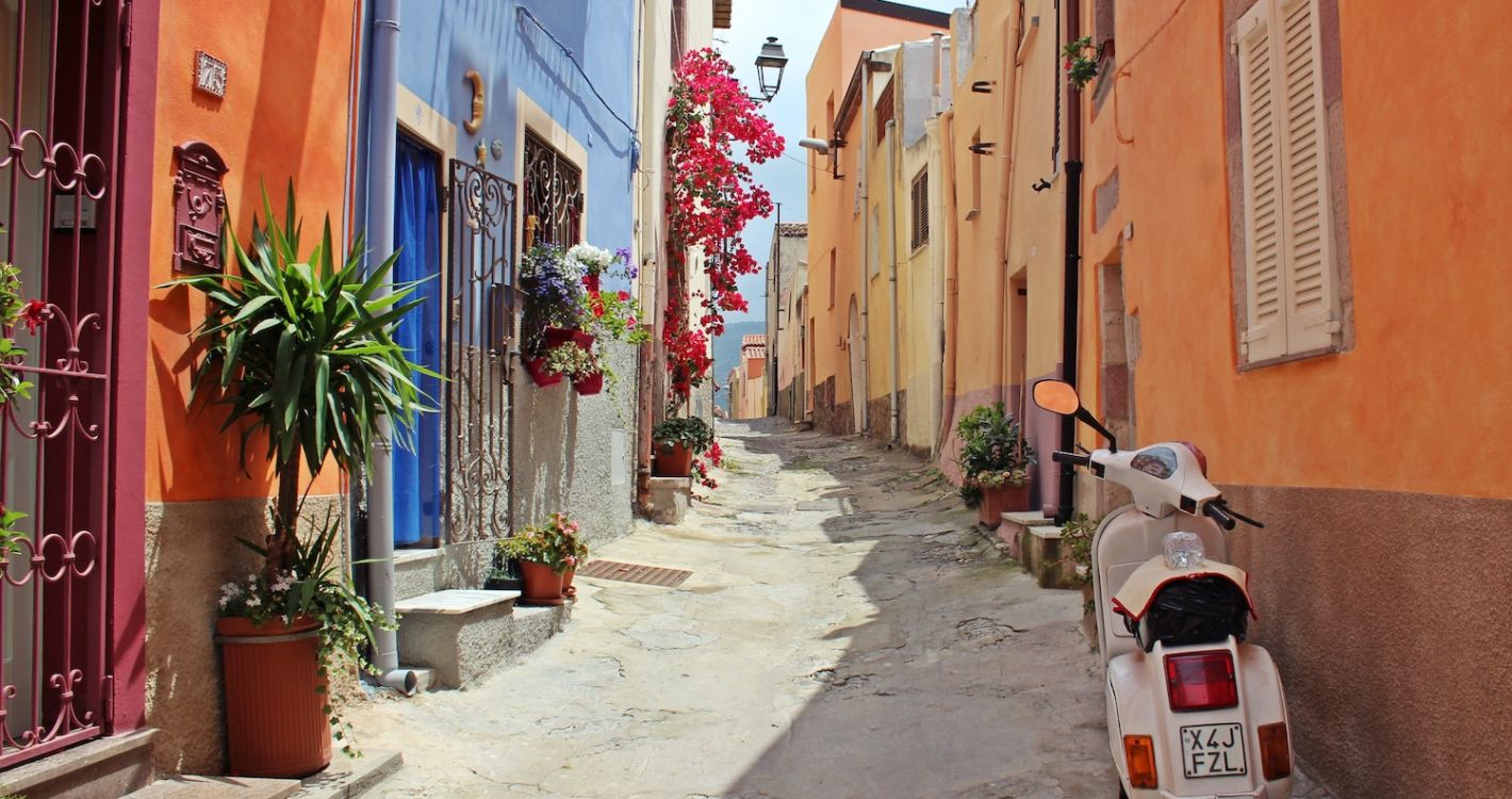 Italië dorpje straatje met gekleurde huizen witte scooter