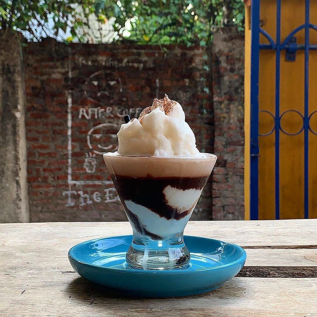 Coconut Coffee in glas, gelaagde koffie met melk en getopt met geschaafd kokosijs van Espresso Station Hoi An