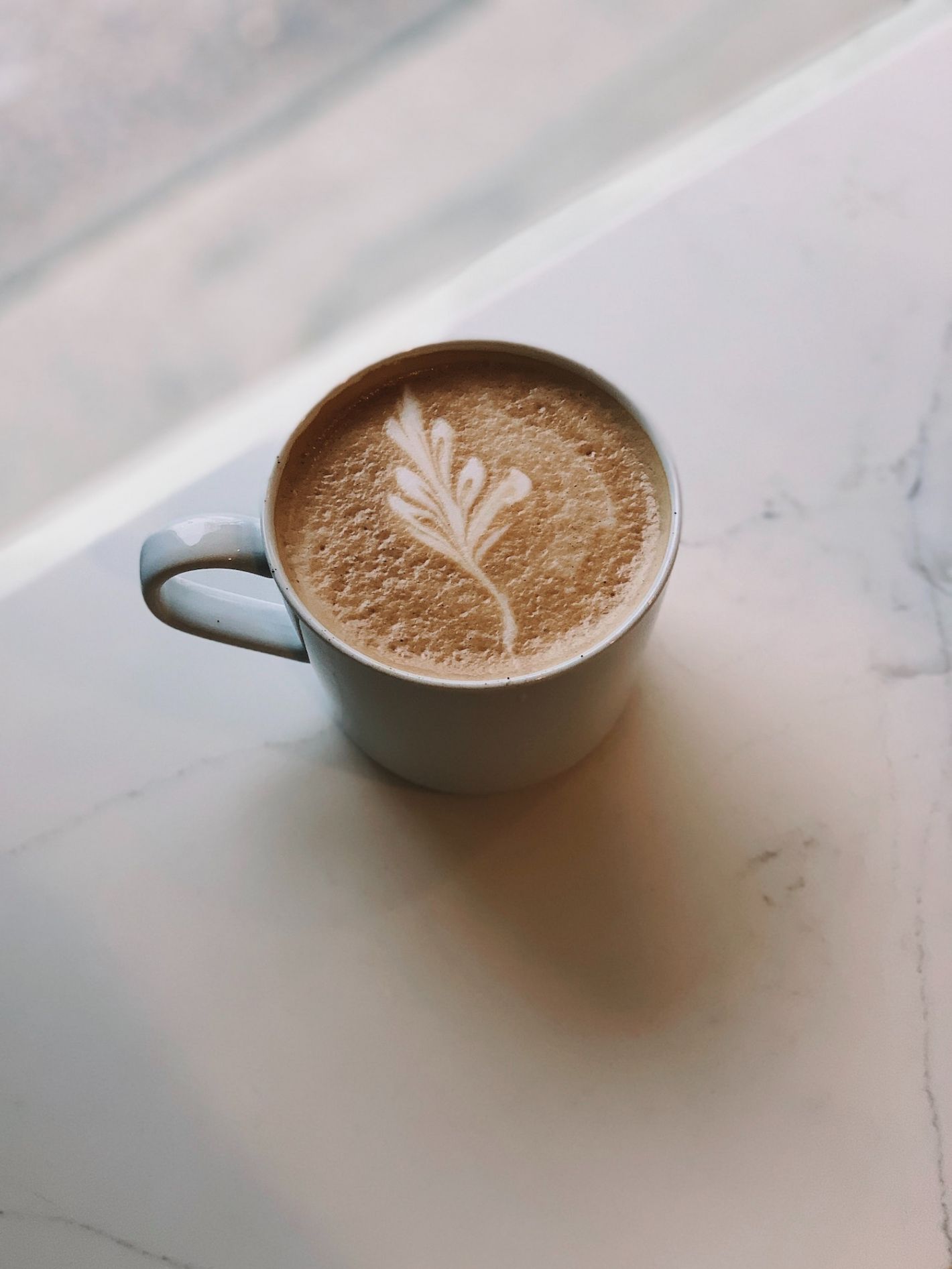 kopje blauw aardewerk koffie met bloem latte art