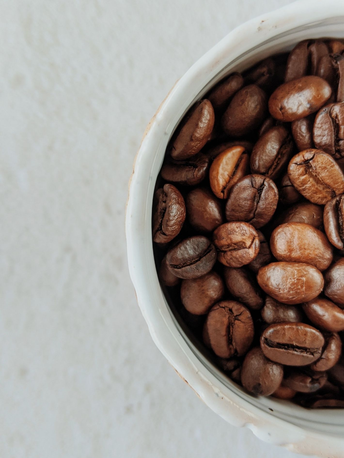 koffiebonen in witte pot op witte tafel