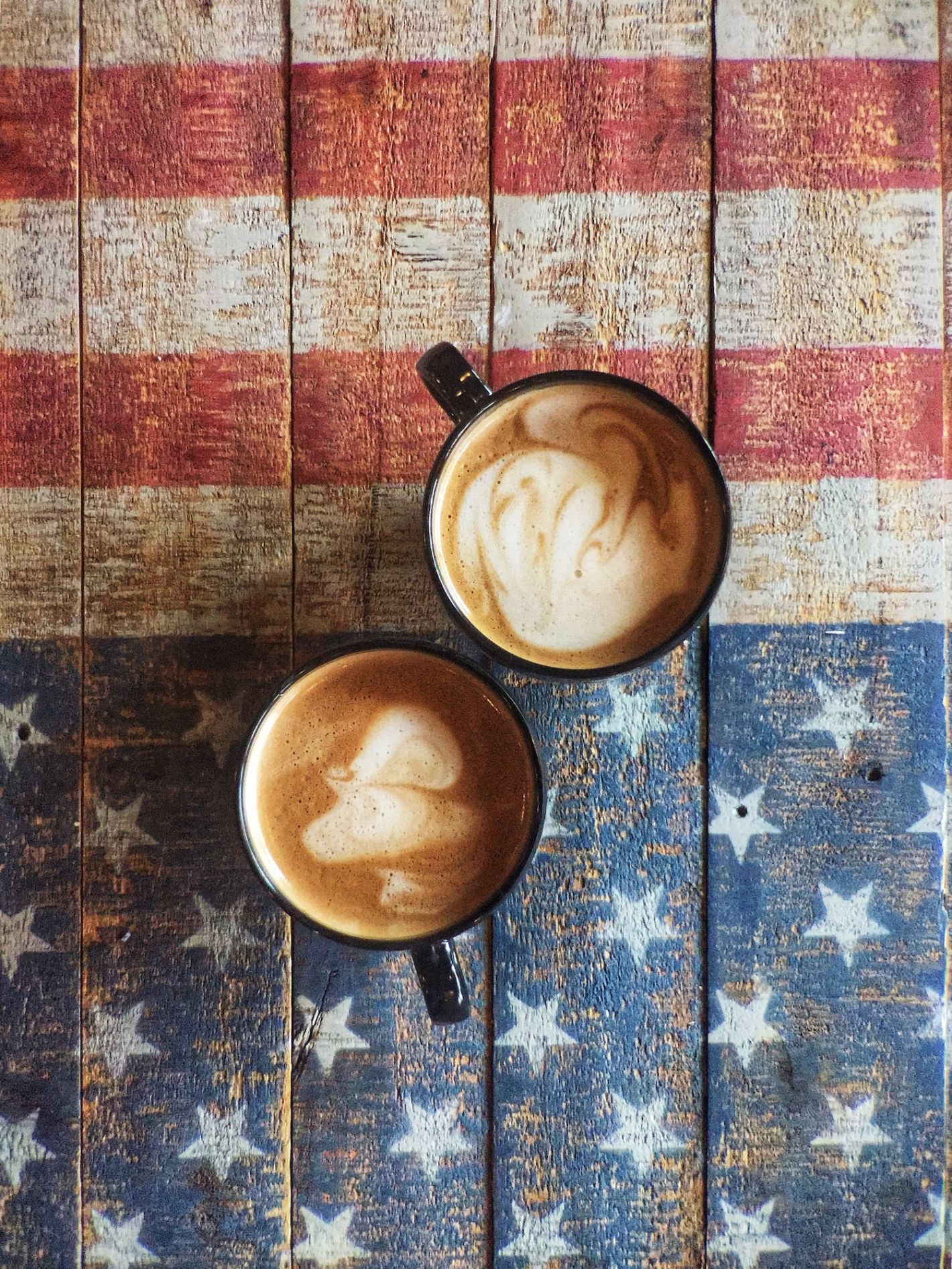 Amerikaanse vlag geschilderd op houten tafel met twee kopjes koffie