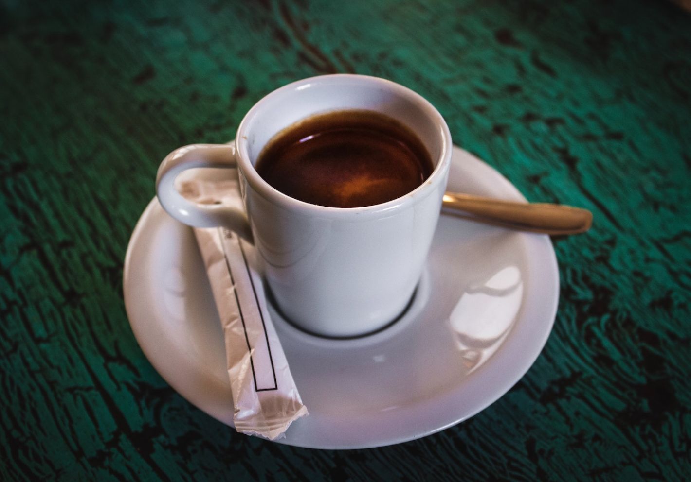 lepeltje kop en schotel wit met espresso