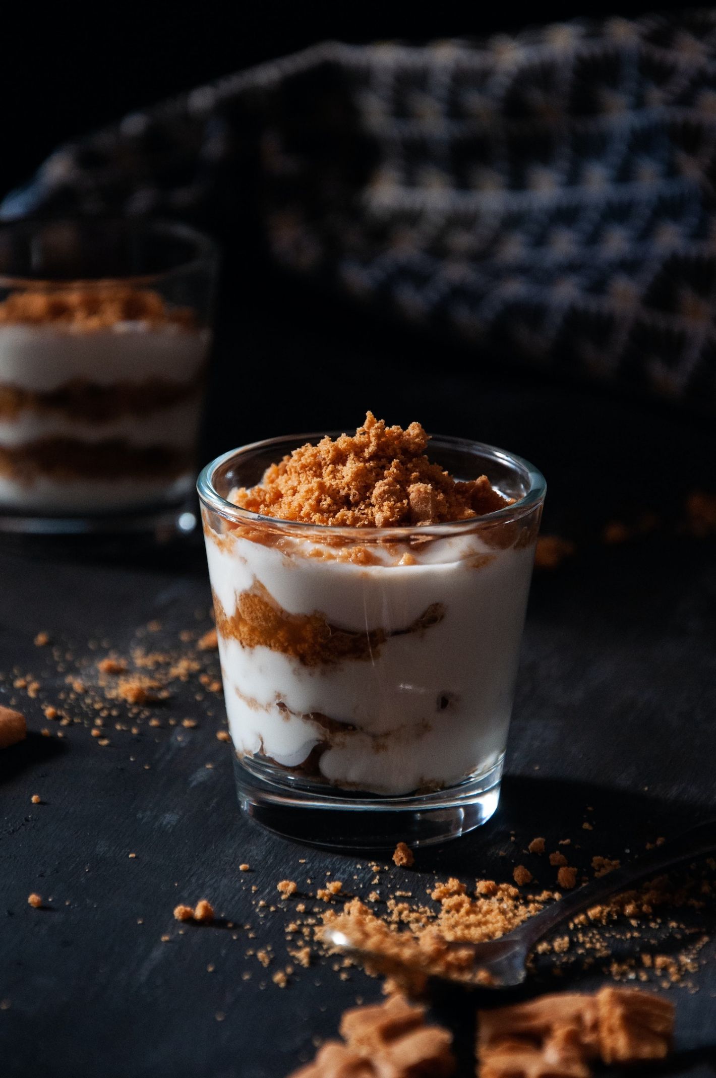 glas met yoghurt en kruimels speculaas op zwarte tafel