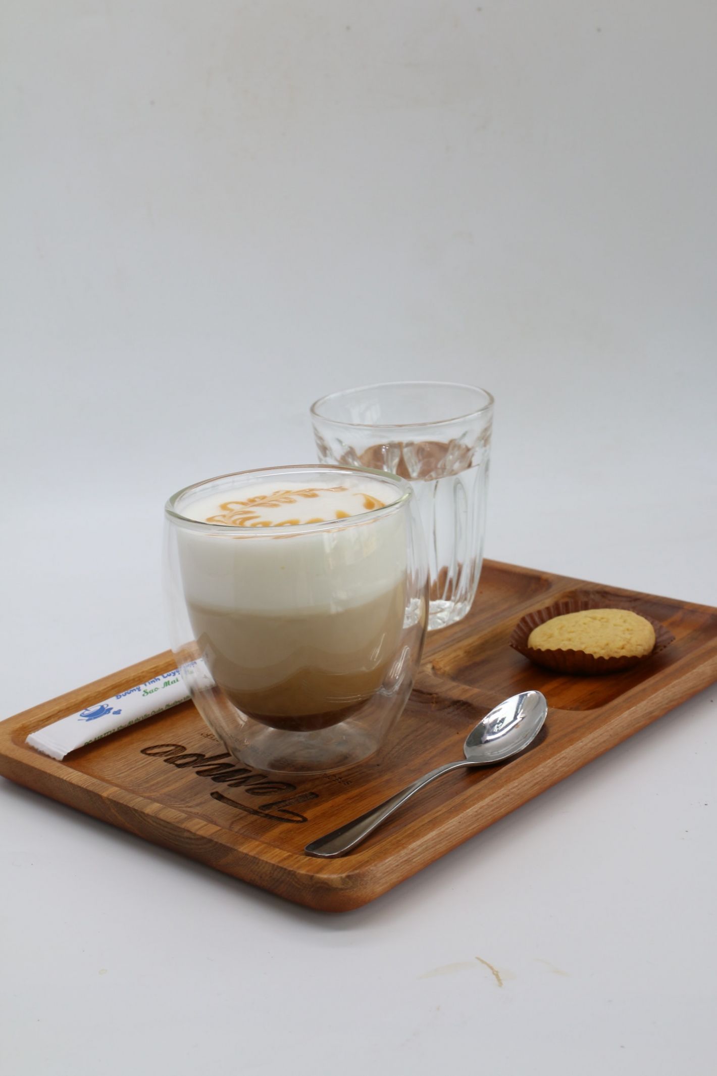 drie lagen koffie in dubbelwandig glas op houten dienblaadje met koekje