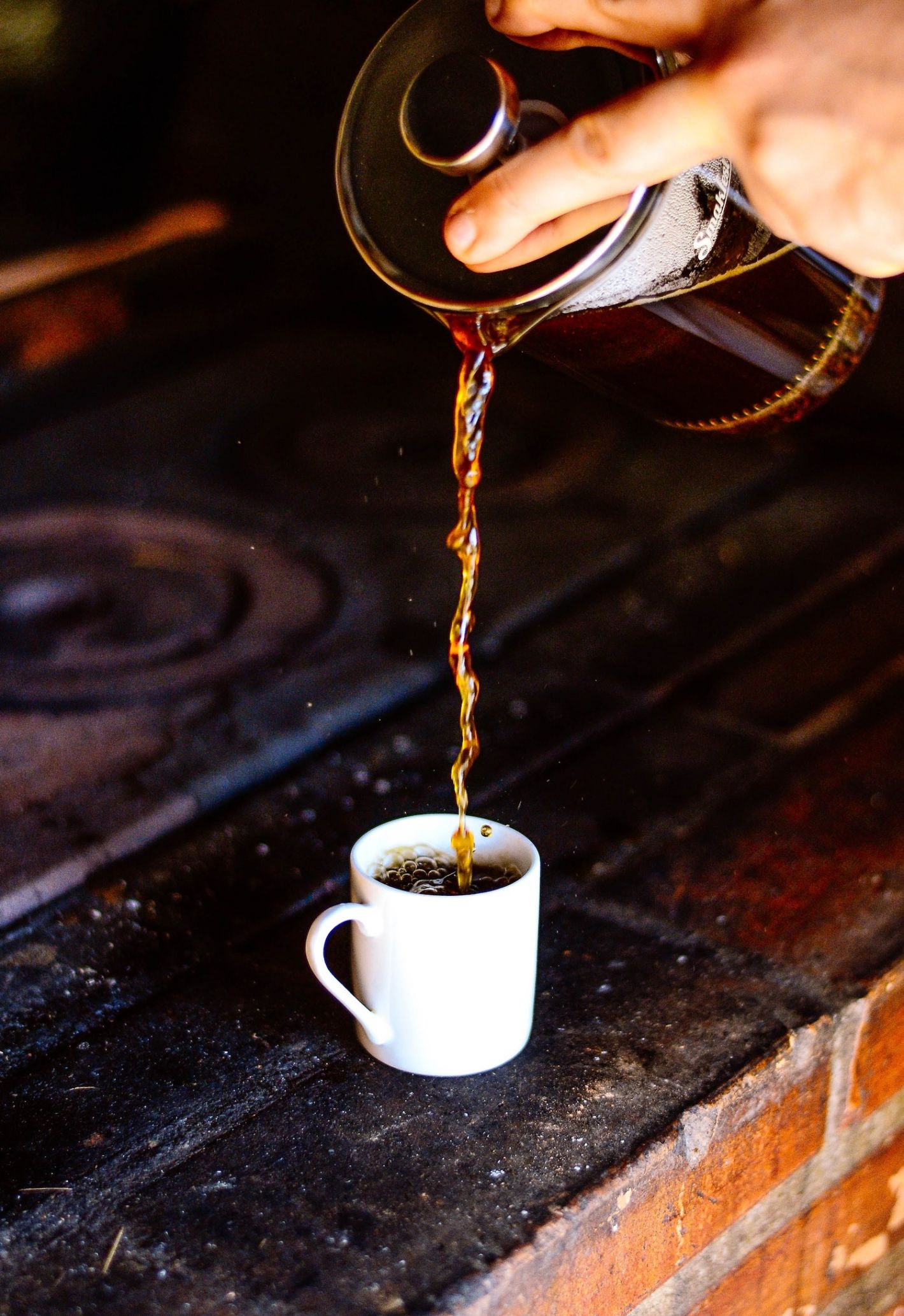 persoon schenkt filterkoffie in wit kopje uit frenchpress